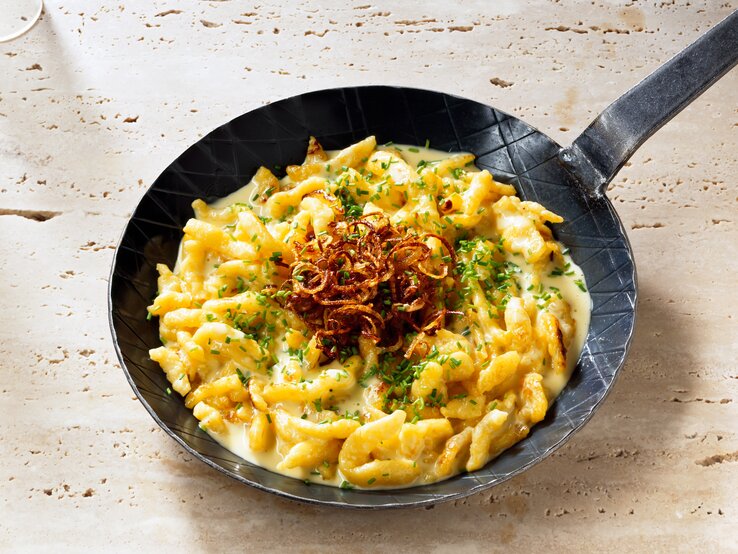 Blick auf eine gusseiserne Pfanne mit Käsespätzle.