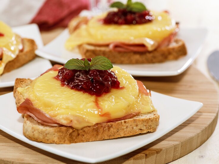 Das Toast Hawaii auf einem weißen Teller und Holzuntergrund. Alles von der Seite fotografiert.