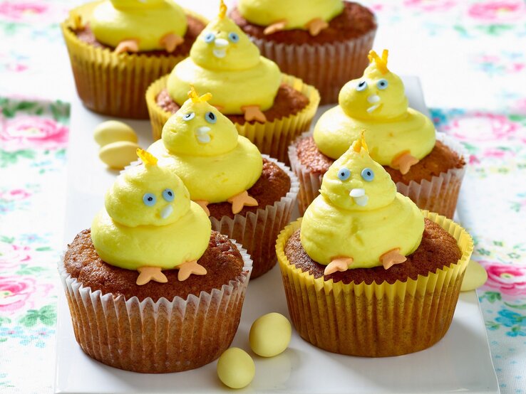 Gelbe Küken-Cupcakes mit blauen Augen und orangen Füßen auf einer Etagere.
