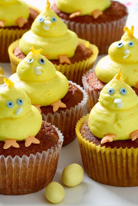 Gelbe Küken-Cupcakes mit blauen Augen und orangen Füßen auf einer Etagere.