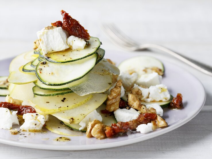 Birnen-Zucchini-Salat mit Ziegenfrischkäse Ein Teller belegt mit Birnen-Salat mit Zucchini, Ziegenfrischkäse und Walnüssen.