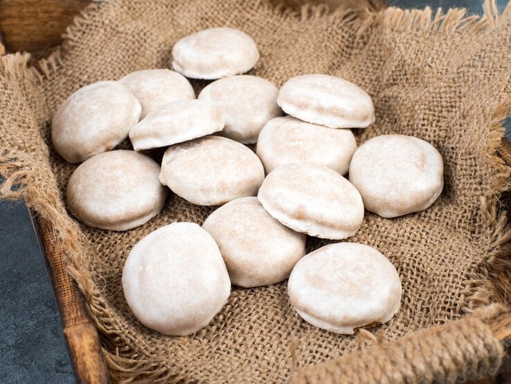 Vierzehn Pfeffernüsse / Untergrund grobes Sackleinen in einer Kiste aus Holz / Draufsicht, schräg