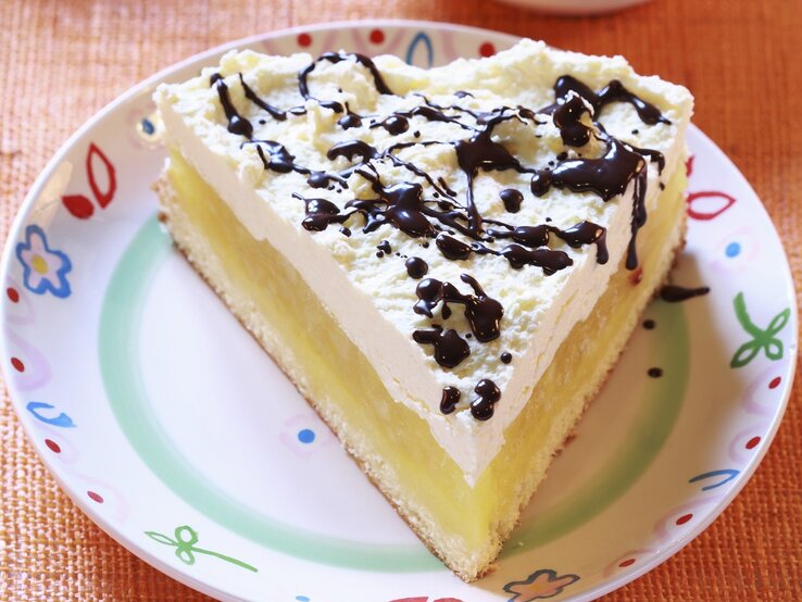 Der Apfelkuchen auf einem bunten Teller mit Schokosoße.