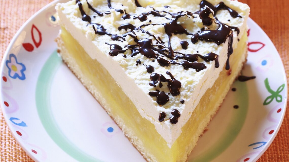 Der Apfelkuchen auf einem bunten Teller mit Schokosoße.