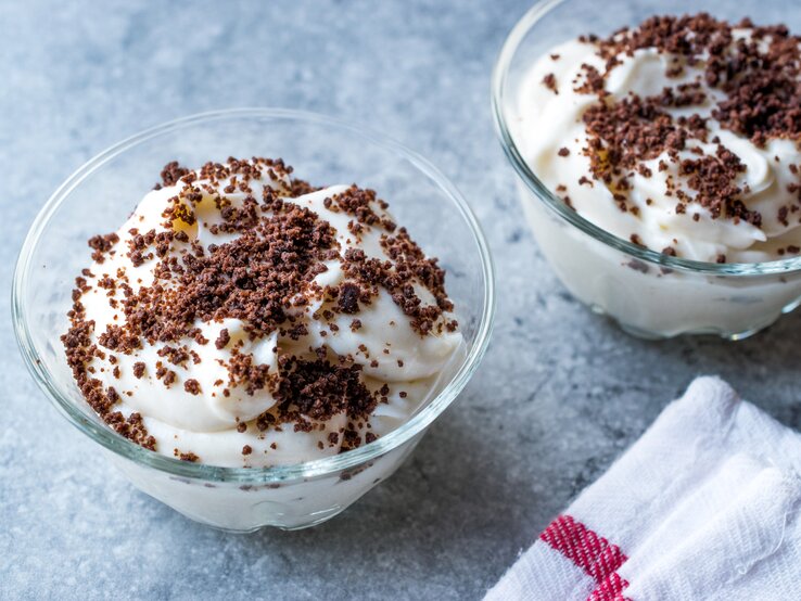 Weiße Quark-Bananen-Creme mit Kekskrümeön auf himmelblauer Oberfläche.