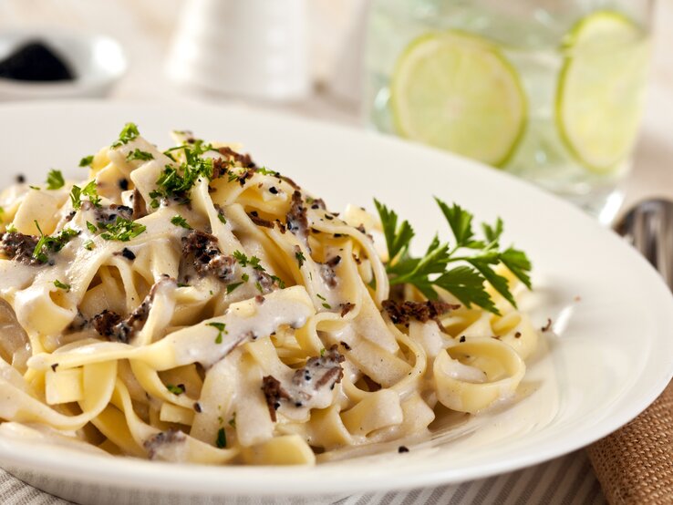 Trueffelpasta Ein weißer Teller, darauf Pasta mit Trüffeln, Parmesan und cremiger Soße.