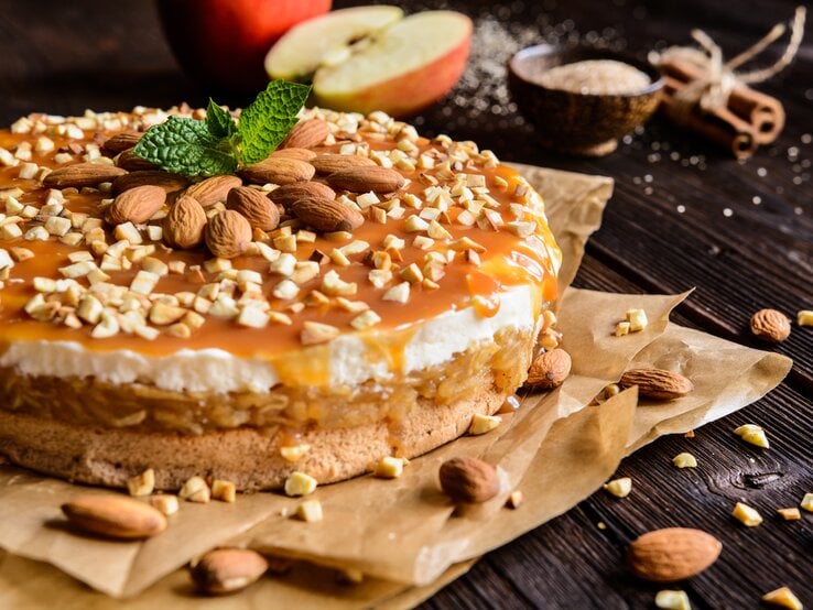 Seitenansicht eines geschichteten, runden Kuchens mit Apfel und Karamellsoße. 