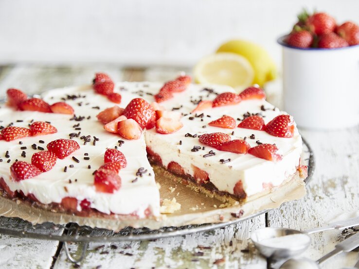 Ansprechende Erdbeertorte mit weißer Creme und dunklen Schokoladenstreuseln, präsentiert auf Holzuntergrund.