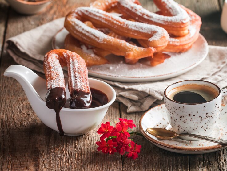 Churros Hufeisenförmiges Brandteiggebäck, getaucht in schokoladiger Soße.