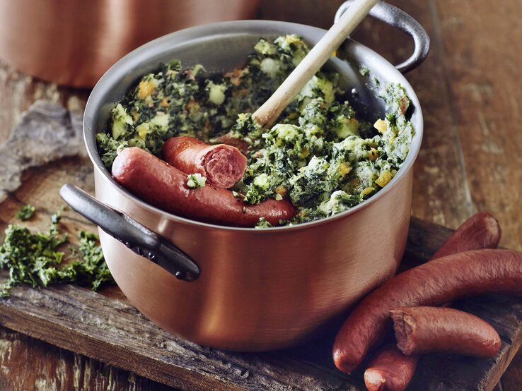 Holländischer Stamppot mit Rauchwurst / Topf aus Kupfer / Holzlöffel / Untergrund Holz / Draufsicht schräg