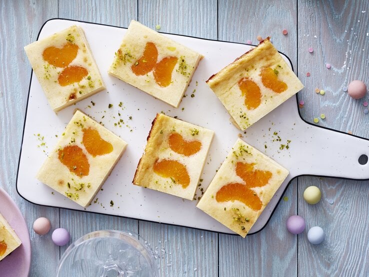 Back dir den Tag schön mit einem Schmetterlings-Käsekuchen, der alles kann! Schmetterlings-Käsekuchen auf einem weißen Schneidebrett vor grauem Hintergrund.
