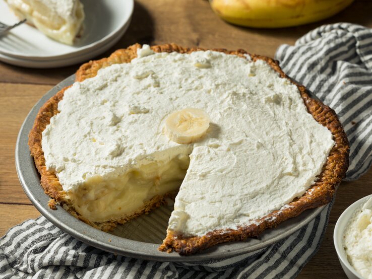 Pie mit bananen-Pudding-Füllung und Schlagsahne auf Holztisch. 