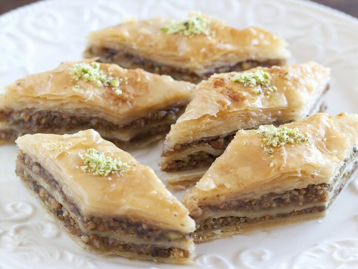 Rautenförmiges Baklava auf einem weißen Pozellanteller nah und von vorne fotografiert