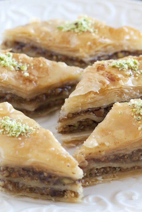 Rautenförmiges Baklava auf einem weißen Pozellanteller nah und von vorne fotografiert