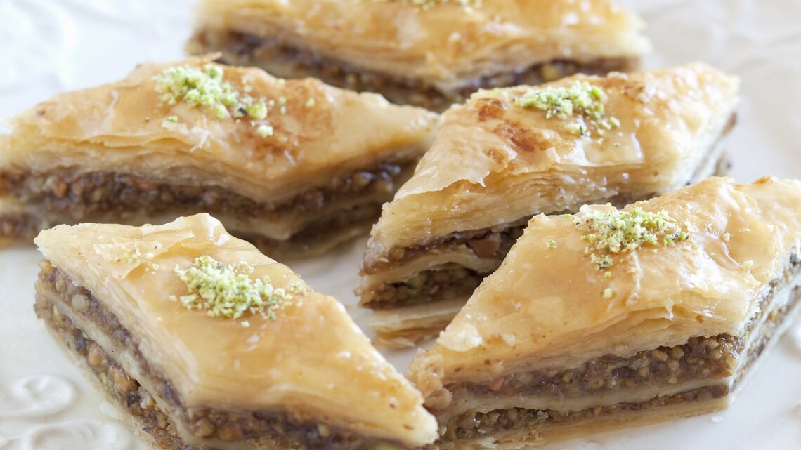 Rautenförmiges Baklava auf einem weißen Pozellanteller nah und von vorne fotografiert