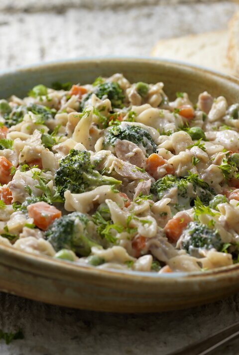 Leckere Nudelpfanne mit Thunfisch und Gemüse in Schale in rustikalem Ambiente.