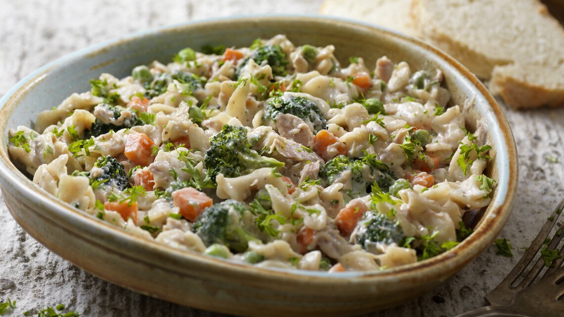 Leckere Nudelpfanne mit Thunfisch und Gemüse in Schale in rustikalem Ambiente.