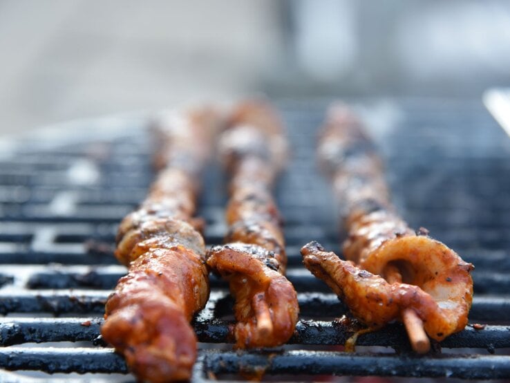 Selbst gemachte Grillfackeln mit Paprikamarinade beim Grillen auf einem Grillrost. Außenaufnahme. Frontalansicht.