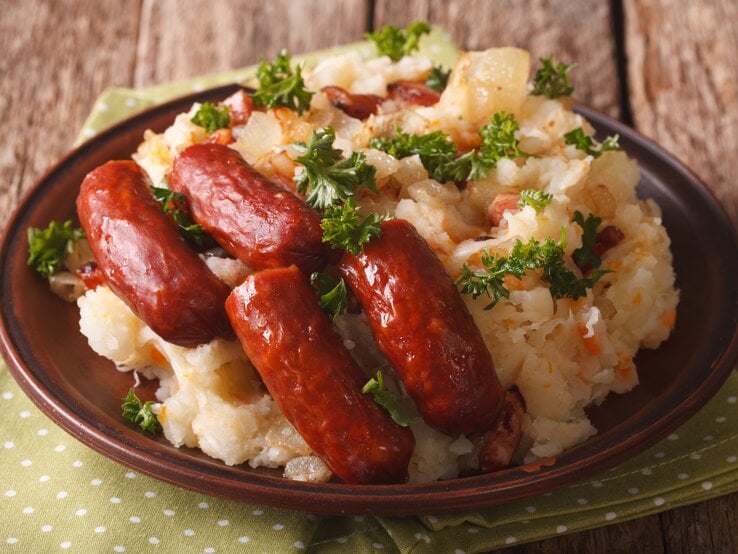 Runder Teller, darauf niederländisches Traditionsgericht Stamppot mit Sauerkraut und Wurst.