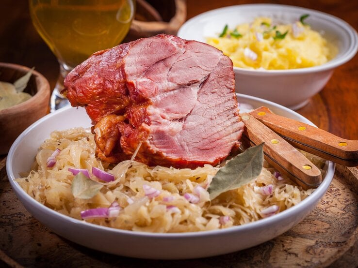 Kasslerbraten auf Sauerkrautbett auf gutbürgerlich gedecktem Tisch.