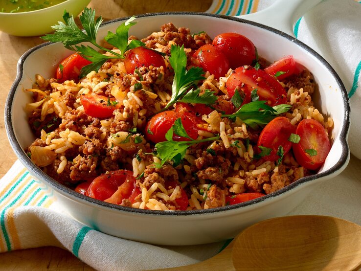 Reispfanne mit Hack und kleinen Tomaten Weiße Schüssel gefüllt mit Reis, Hackfleisch und kleinen Tomaten.