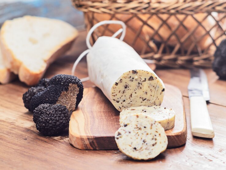 trueffelbutter Angeschnittene Rolle Trüffelbutter arrangiert auf einem Holzbrett.