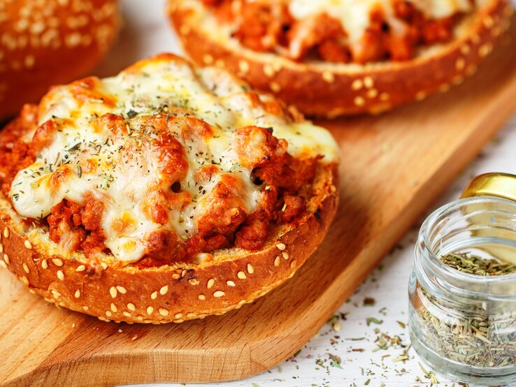 Pizzabrötchen mit Hackfleisch und Käse auf Holzbrett. 