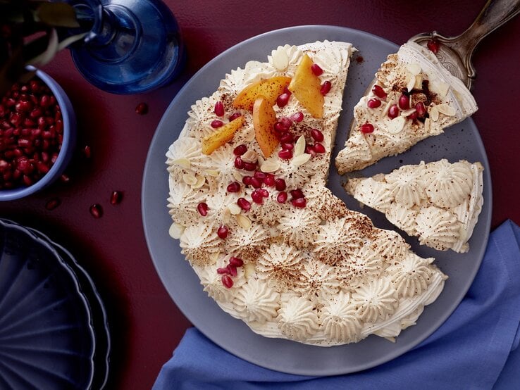 Die Mokka-Baiser-Joghurttorte auf einem dunkelblauem Teller und Untergrund. Direkt von oben fotografiert.