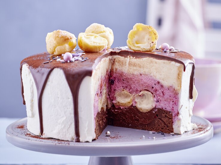 Die angeschnittene Torte auf einem grauen Kuchenständer mit unscharfem Hintergrund sehr nah fotografiert