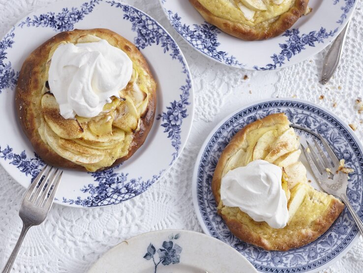 Die Apfel-Pizetten auf blau-weißen Tellern und weißer Tischdecke. Alles direkt von oben fotografiert.