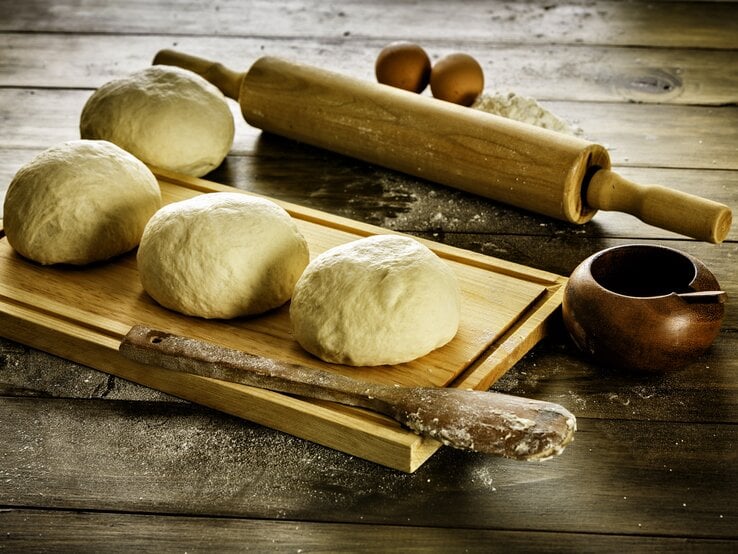 Mehrere Teigbälle auf Holzbrett. 