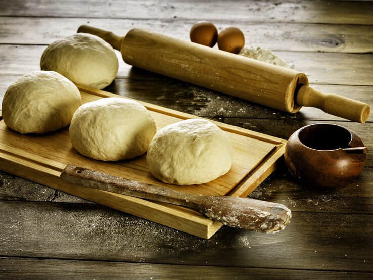 Mehrere Teigbälle auf Holzbrett. 