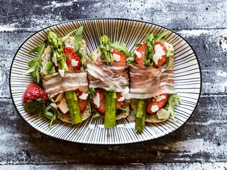 Bruschetta belegt mit Spargel, Erdbeeren, Rucola, Parmaschinken und Parmesan.