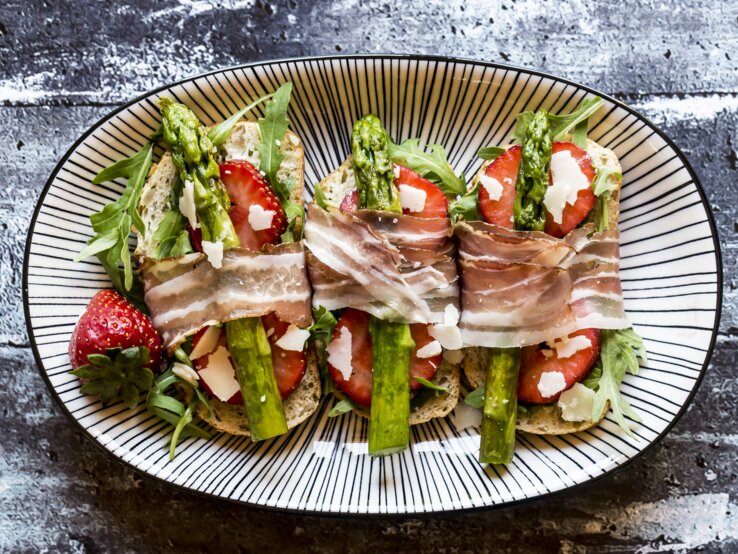 Bruschetta belegt mit Spargel, Erdbeeren, Rucola, Parmaschinken und Parmesan.