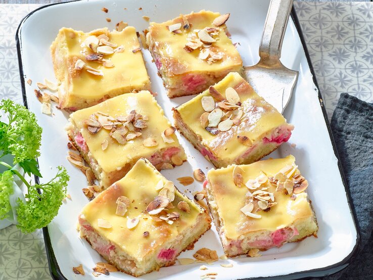 Rhabarber-Mandelkuchen mit Eierlikör in einer weißen Backform auf grauem Hintergrund. 