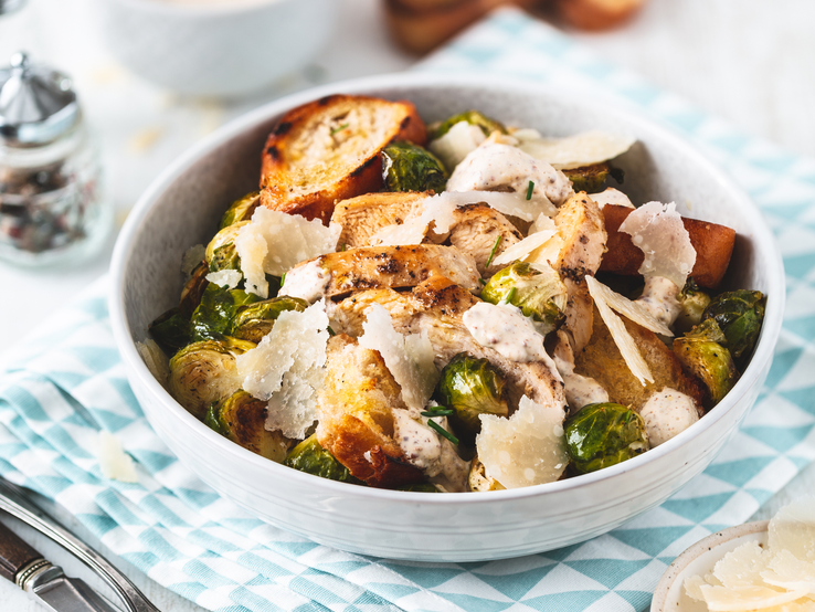 Runde Schale gefüllt mit Rosenkohl, krossen Brotscheiben und Parmesan. 