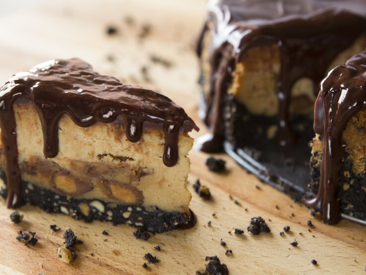 Erdnussbutter-Käsekuchen mit flüssiger Schokosoße auf hölzernem Untergrund.