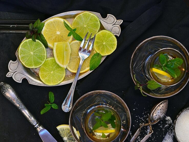 Limetten-Heißgetränk von oben aufgenommen neben Tablett mit Limettenscheiben. 