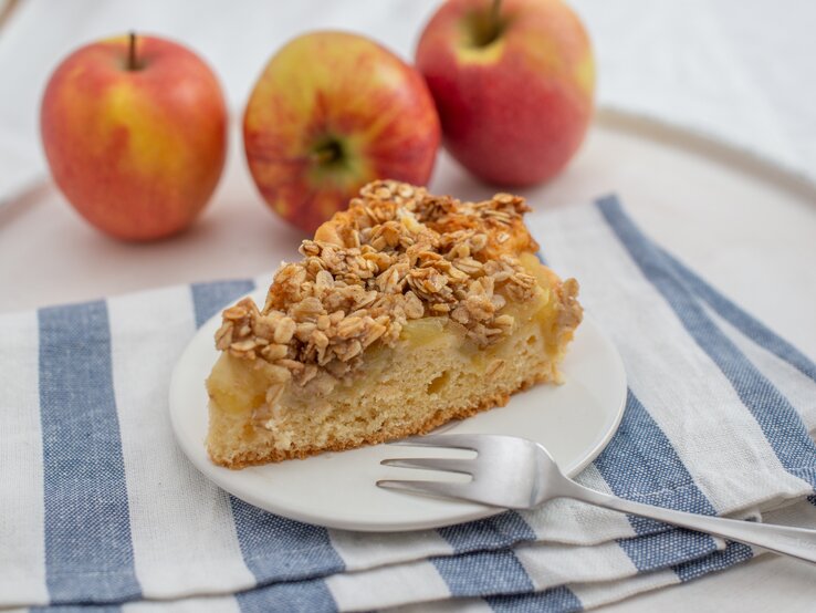 Ein Stück Apfelkuchen mit Haferflockentopping auf Teller.