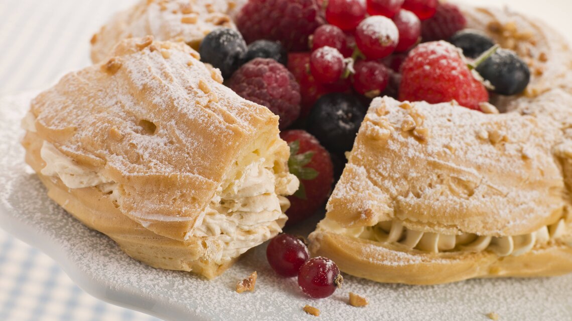 Seitliche Ansicht eines Paris Brest Kuchens, garniert mit Beeren.
