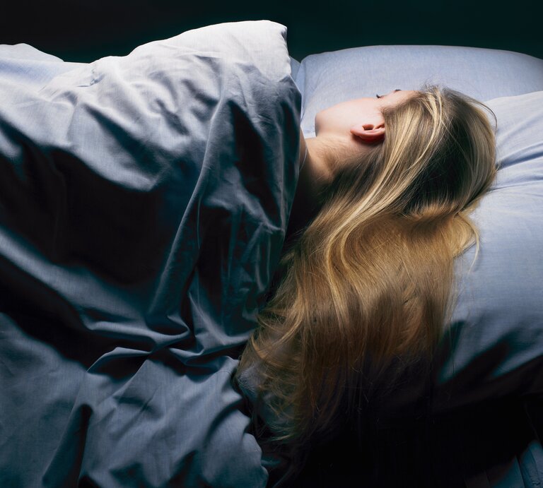 Frau schläft seitlich im Bett. | © Getty Images/Ghislain & Marie David de Lossy