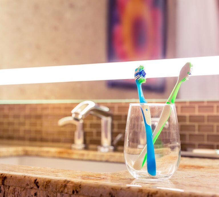 Ein Glas mit zwei Zahnbürsten steht neben dem Waschbecken. | © Getty Images / Nomadsoul1