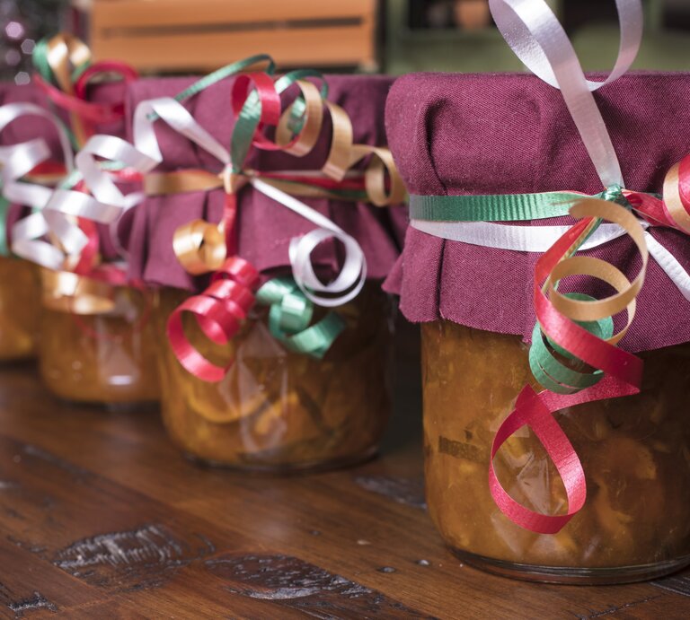 Selbst gemachte Marmeladen in Gläsern stehen mit Schleifen und lila Stoff auf dem Tisch. | © Getty Images/Malisa Nicolau