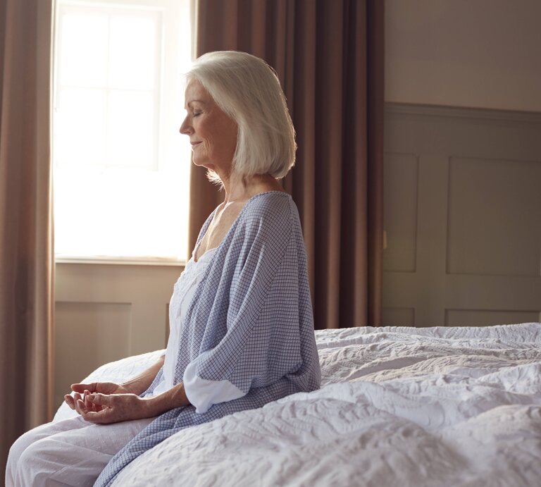 Eine Dame startet achtsam mit Meditation in den Tag. | © IMAGO / Shotshop