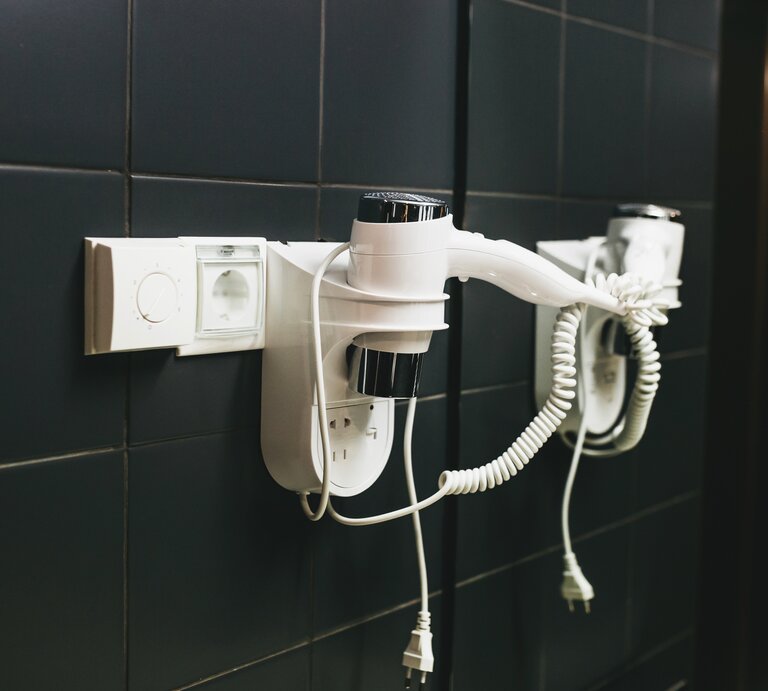 Ein Föhn hängt im Hotelzimmer an der Wand. | © Getty Images /franz12 