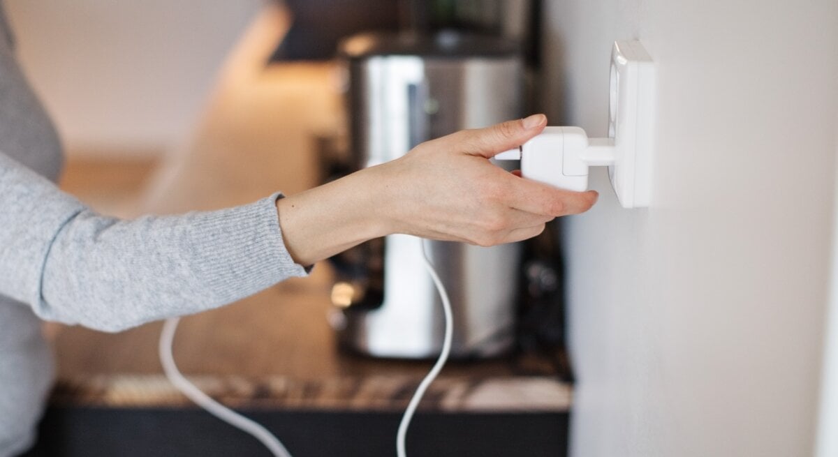 Eine Frau steckt einen Stecker in eine Steckdose.