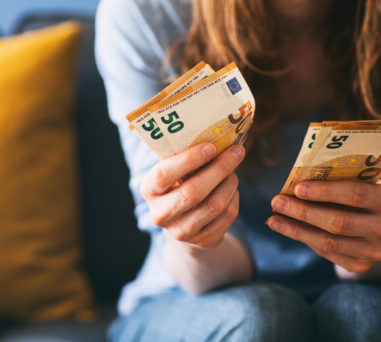 Rothaarige Frau hat mehrere Geldscheine in der Hand. | © AdobeStock/ ptnphotof