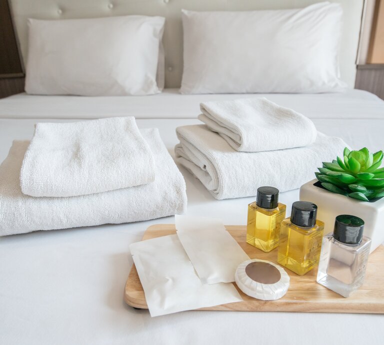 Shampoo-Proben liegen schön dekoriert auf dem Hotelbett. | © shutterstock/ Boyloso