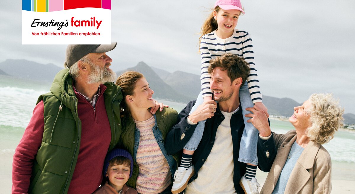 Eine glückliche Familie geht am Strand spazieren.