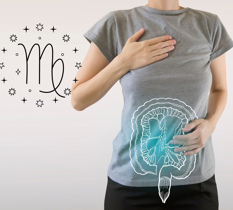 Das Bild zeigt eine Frau in einem grauen T-Shirt, die eine Hand auf ihre Brust und die andere auf ihren Bauch legt. Auf ihrem Bauch ist eine schematische Zeichnung des Verdauungssystems zu sehen, die auf das T-Shirt projiziert ist. Links neben ihr ist das astrologische Symbol für Jungfrau (Virgo) umgeben von kleinen Sternen abgebildet. | © Getty Images/ mi-viri und warmjuly via Canva.com [M]